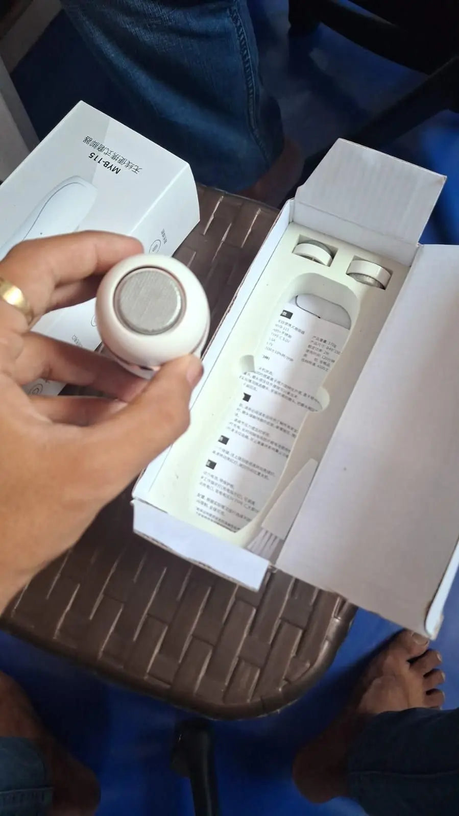 Electric foot scrubber in hand with packaging on table for easy foot care at home