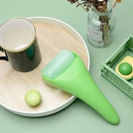 Green reduce puffiness ice roller on a wooden tray next to a cup and decorative items