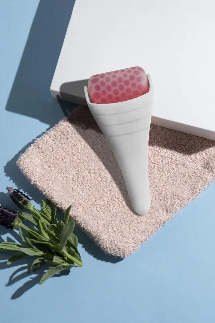 White reduce puffiness ice roller on soft towel with pink accents for skincare routine